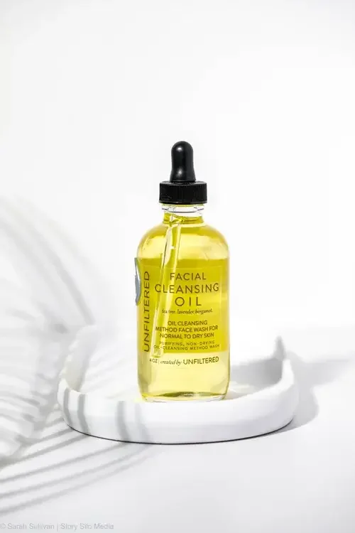  A bottle of organic cleansing oil placed on a white plate, showcasing its sleek design and natural ingredients.
