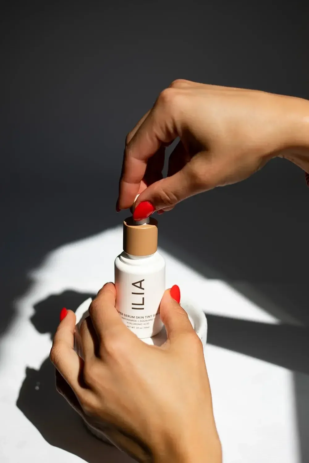 A woman holds a bottle of Lila skin care, showcasing the product's elegant design and her radiant smile.