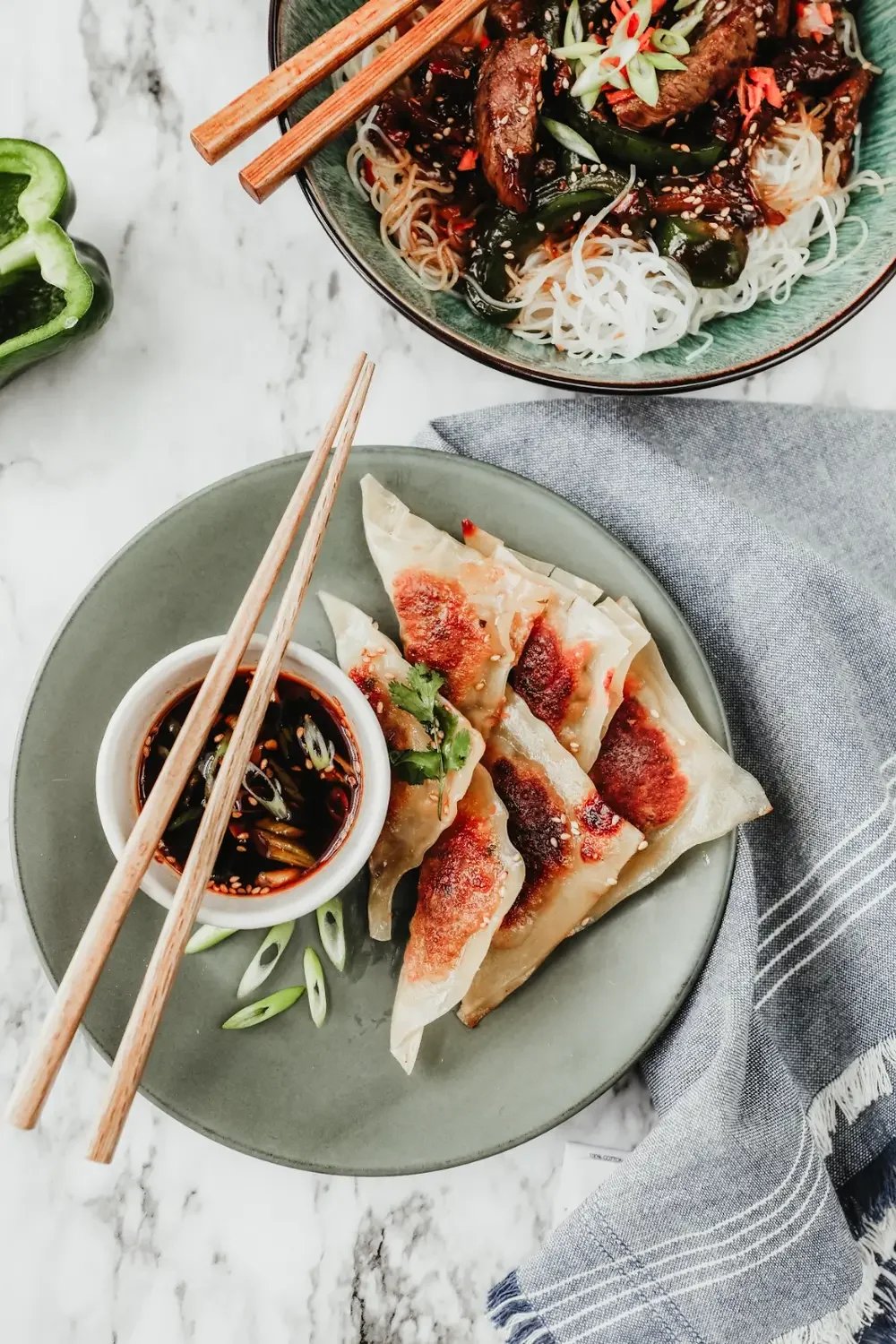  A plate of Chinese beef dumplings accompanied by a colorful assortment of Asian vegetables.
