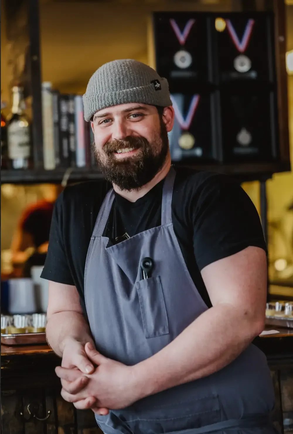 A smiling man with a beard wearing a hat, exuding a friendly and cheerful demeanor.
