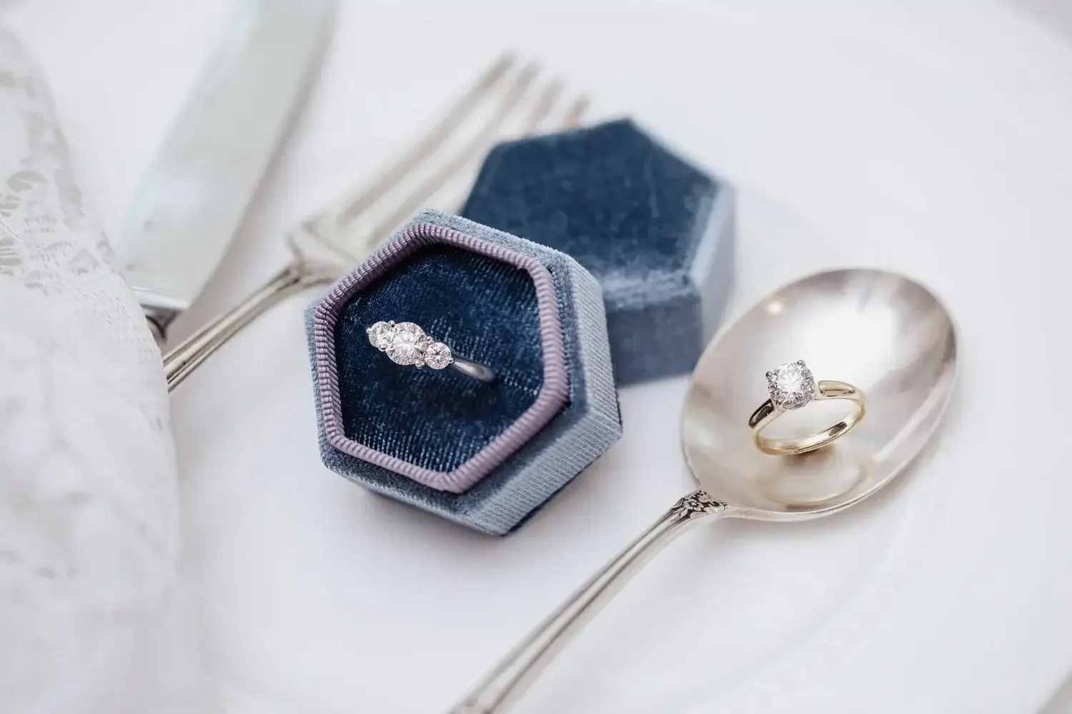  A wedding ring rests on a silver plate, accompanied by a knife and fork, symbolizing a celebratory meal.