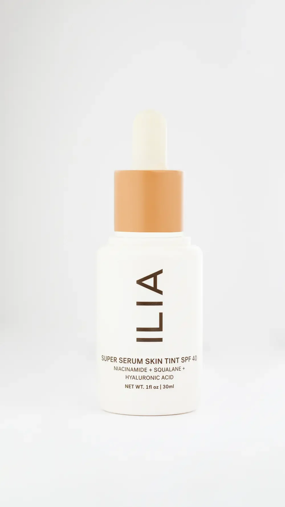  Ila Super Serum for skin tone enhancement, featuring a sleek bottle with a dropper, set against a neutral background.
