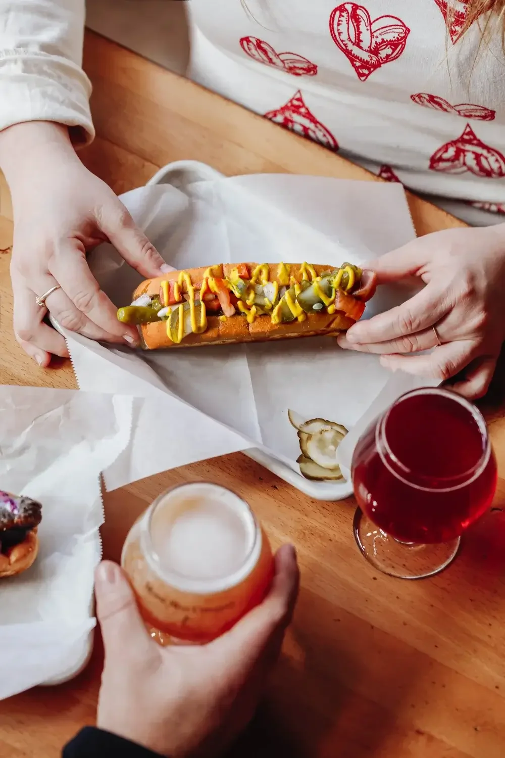  A table set with a hot dog, a bottle of beer, and a glass of beer, ready for a casual meal.