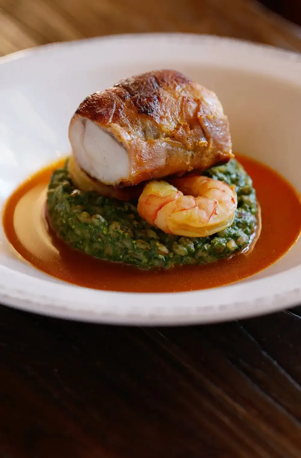 A plate featuring a dish of food elegantly placed atop a vibrant green sauce.
