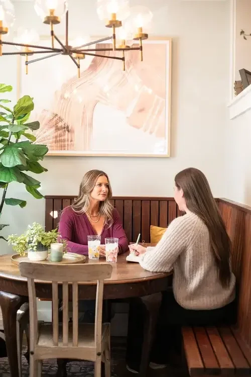 Two women engaged in conversation while sitting at a table in a restaurant, enjoying their meal together