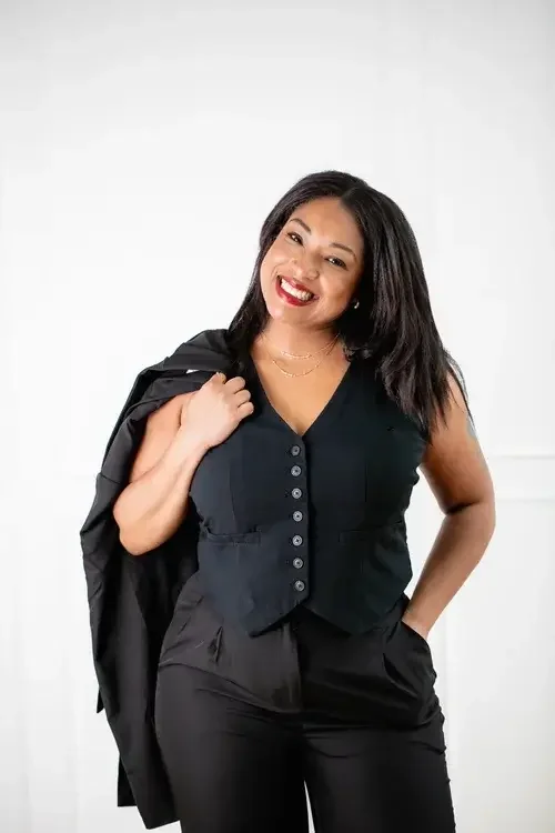  A woman wearing black pants and a black top stands confidently, showcasing a stylish and modern outfit.

