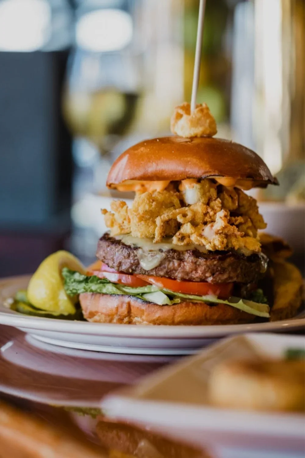 A hamburger with lettuce and tomato, accompanied by a side of golden fries and a refreshing drink.
