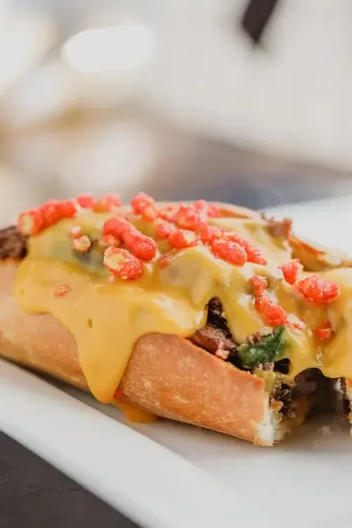 A sandwich featuring layers of cheese and sliced red peppers on a toasted bread.
