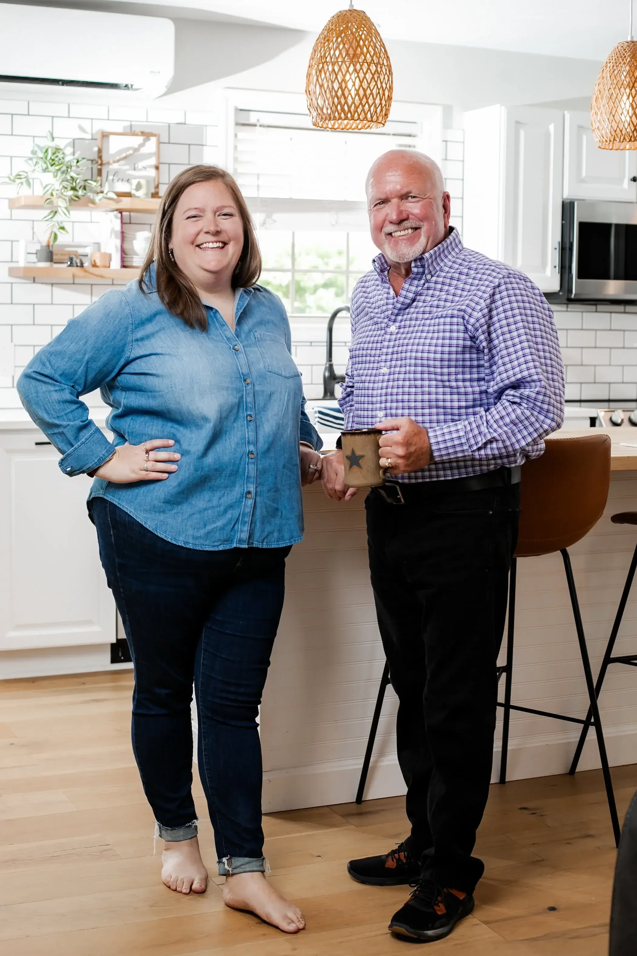 A man and woman stand together in a kitchen, holding a coffee cup, smiling at each other.
