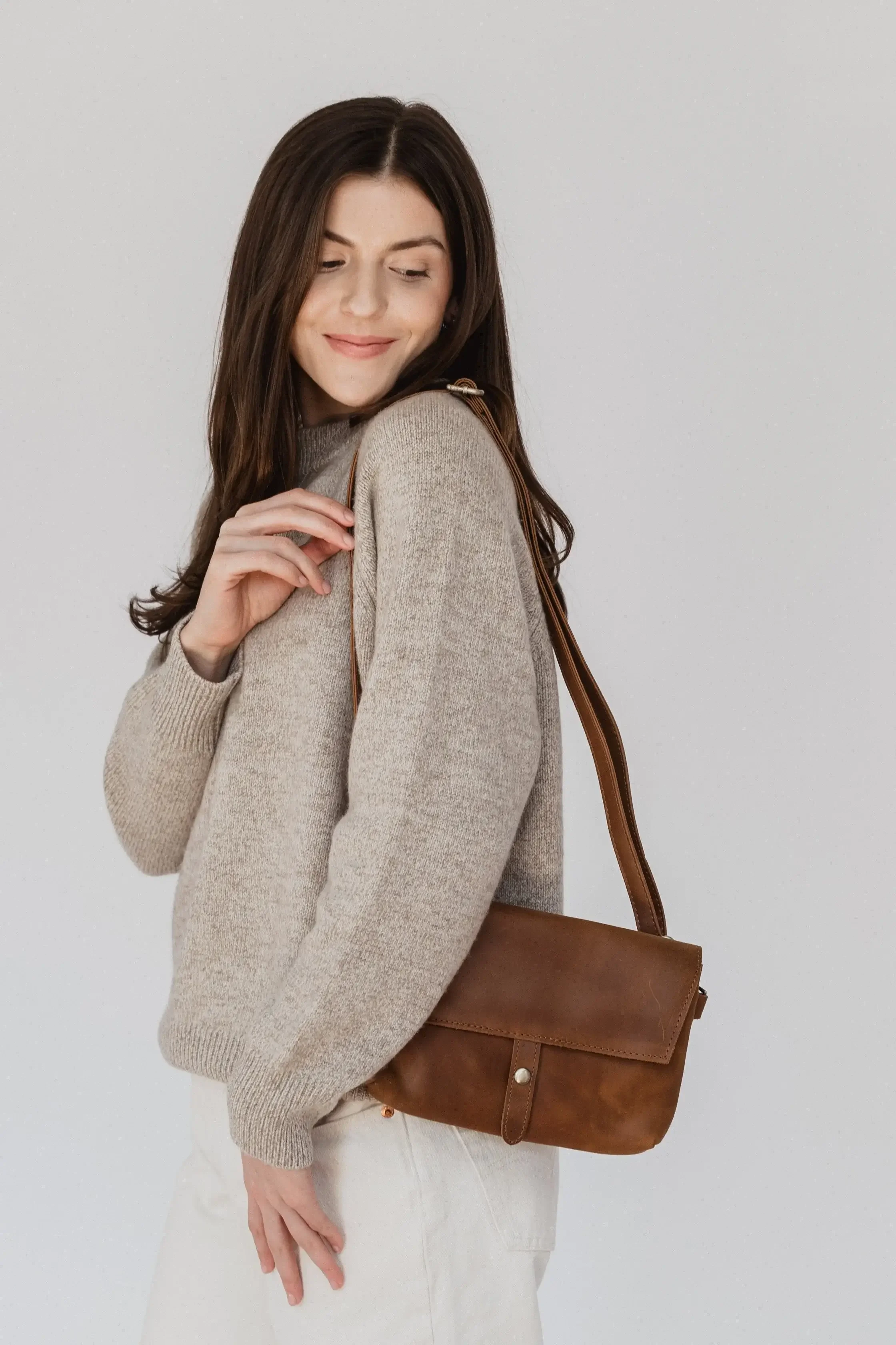 Brown leather crossbody bag with a sleek design and adjustable strap, ideal for casual or formal outings.