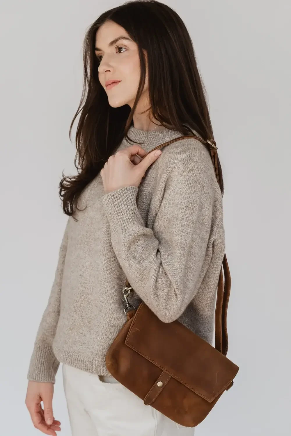 A small tan leather crossbody bag with a sleek design and adjustable strap, ideal for casual outings.
