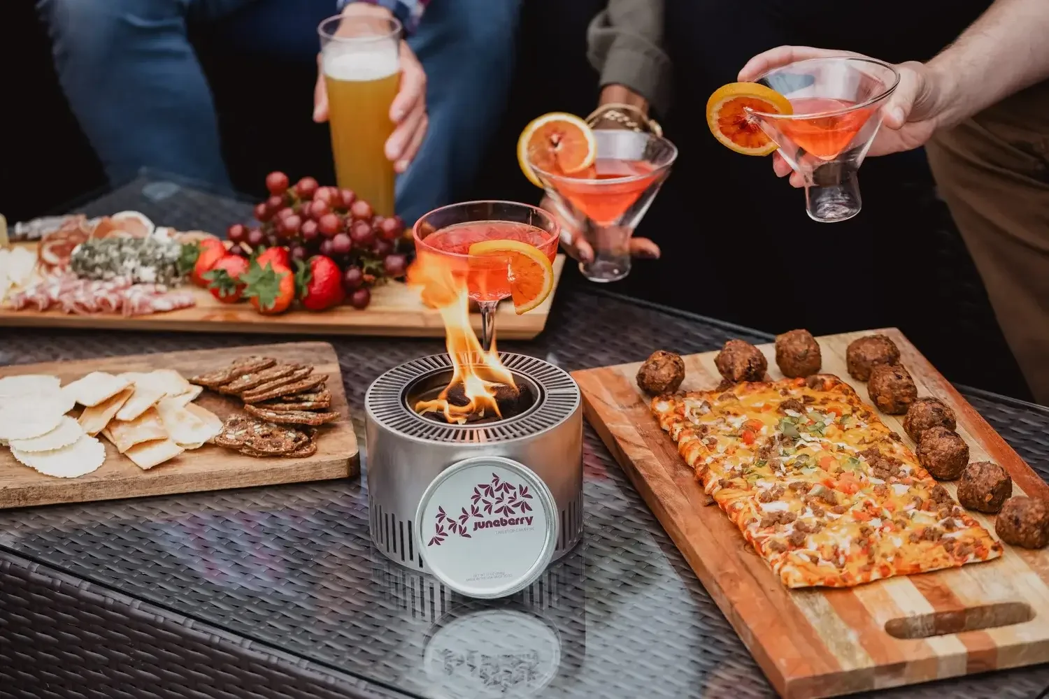  A group of people gathered around a table, enjoying drinks and food together in a social setting.
