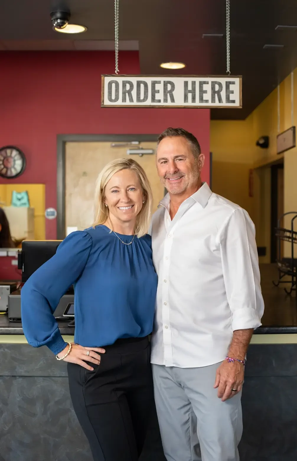 A man and woman pose together in front of a restaurant sign, smiling and enjoying their time.