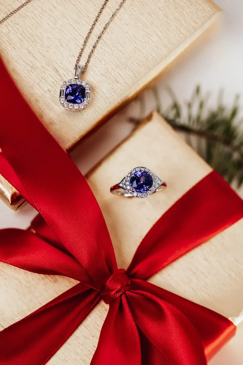 A pair of blue sapphire rings displayed elegantly alongside a vibrant red ribbon.
