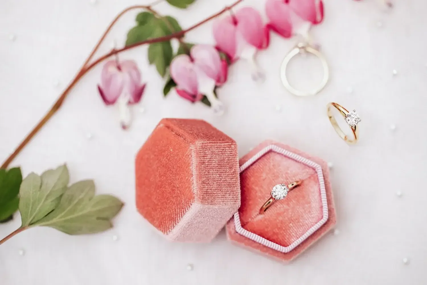 A pink velvet box containing a sparkling diamond engagement ring and a matching wedding band.
