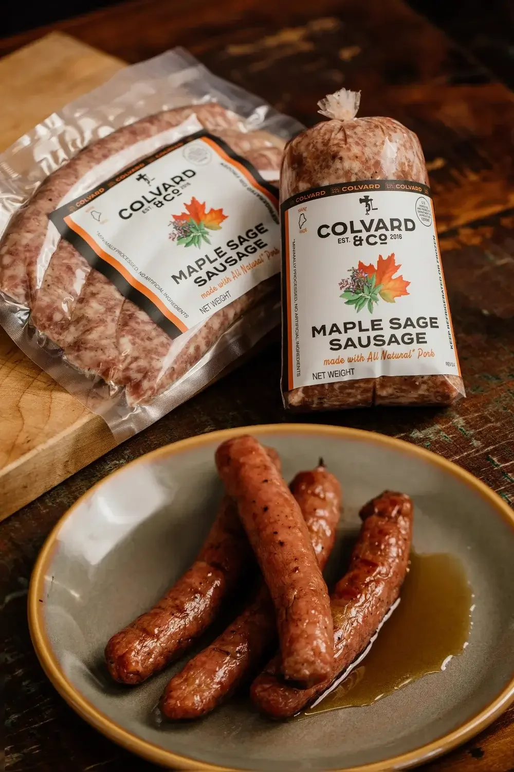 A plate filled with cooked sausages alongside a bag of maple-flavored sausages.
