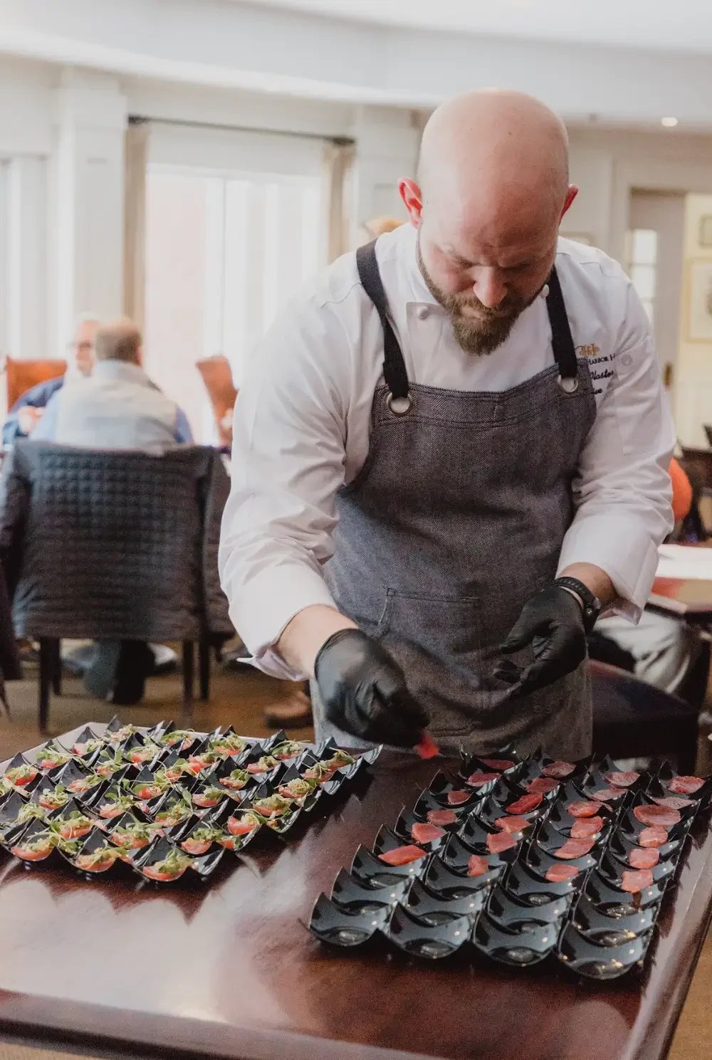  A man in a chef's apron skillfully prepares food on a kitchen counter, surrounded by fresh ingredients and utensils.
