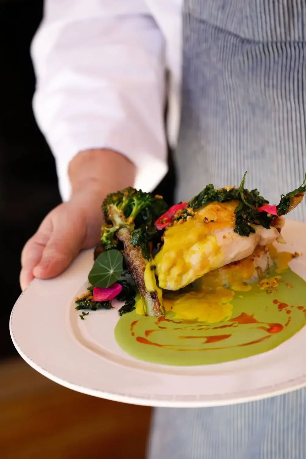  A chef proudly presents a plate of gourmet food, showcasing culinary skills and artistry.
