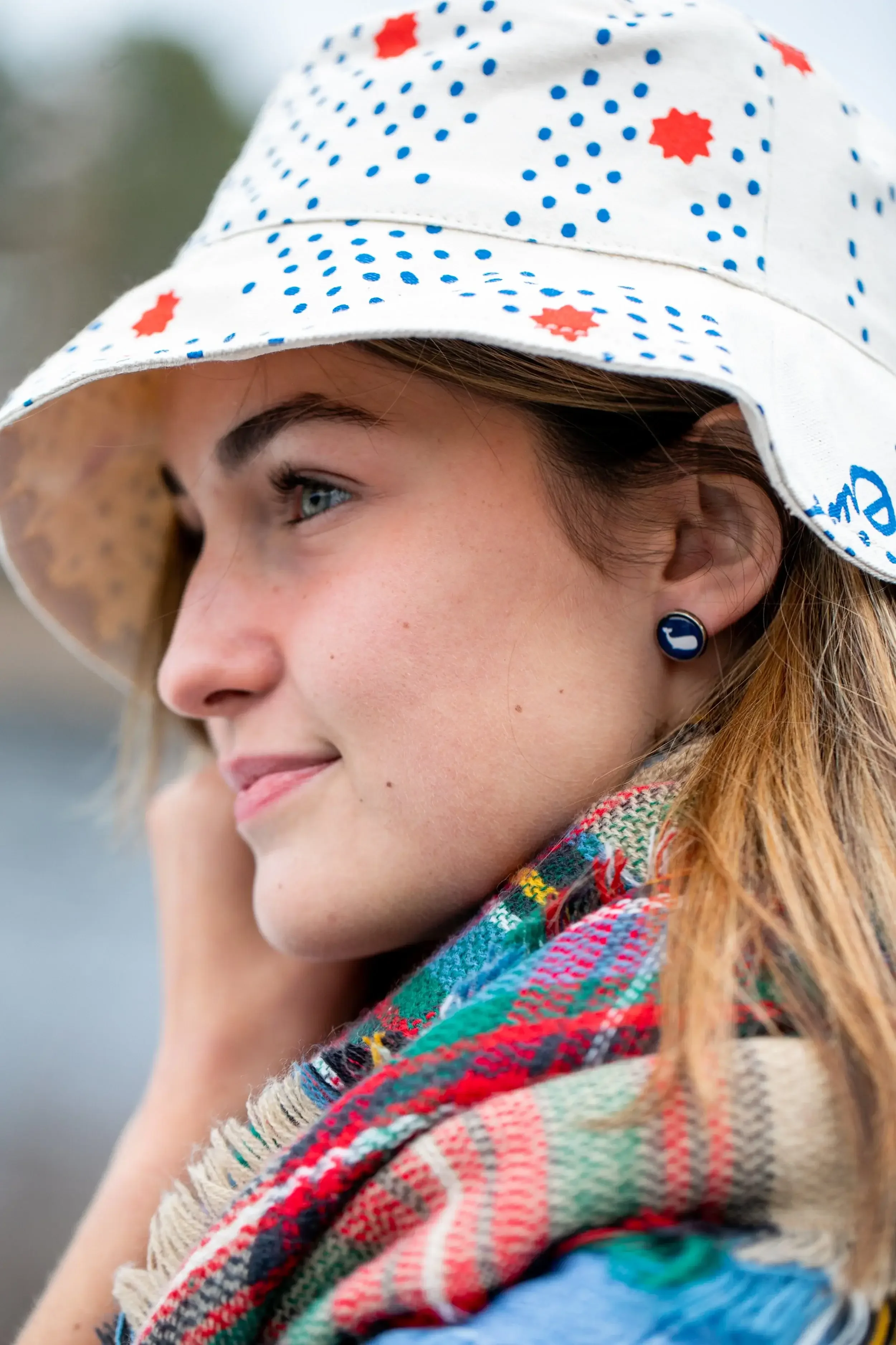 A woman wearing a stylish polka dot hat, smiling and looking towards the camera.
