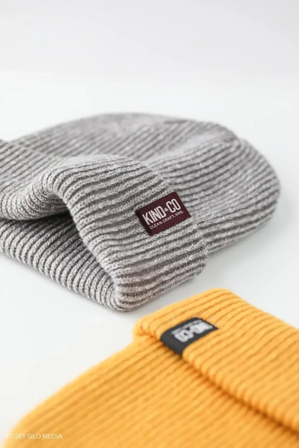  A gray and yellow beanie featuring a tag, showcasing a stylish winter accessory.