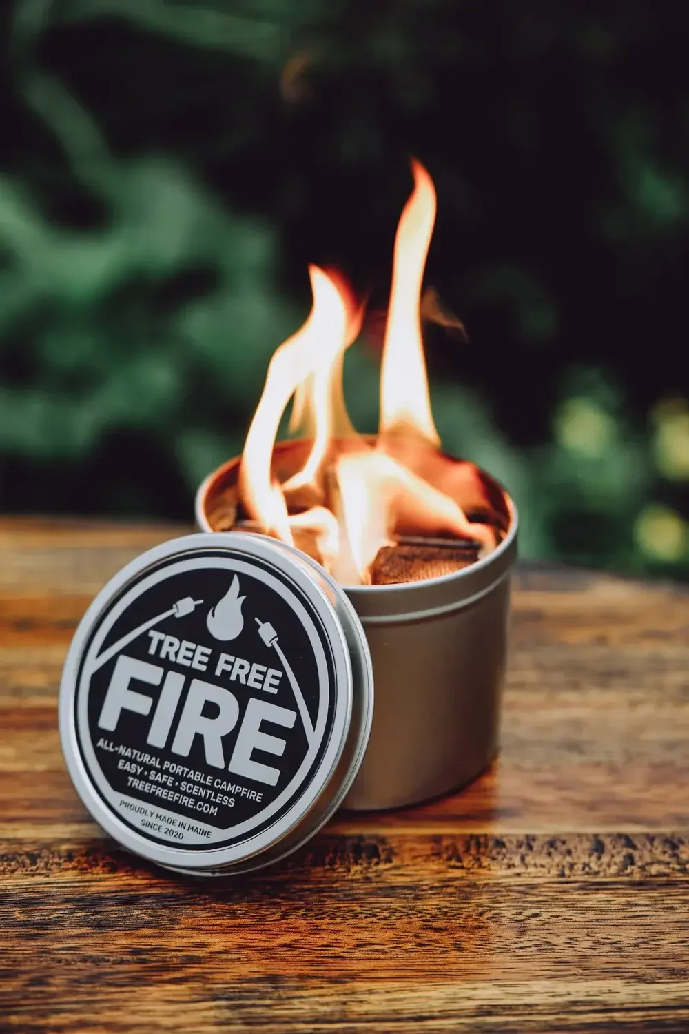  A tin container filled with firewood placed on a rustic wooden table.
