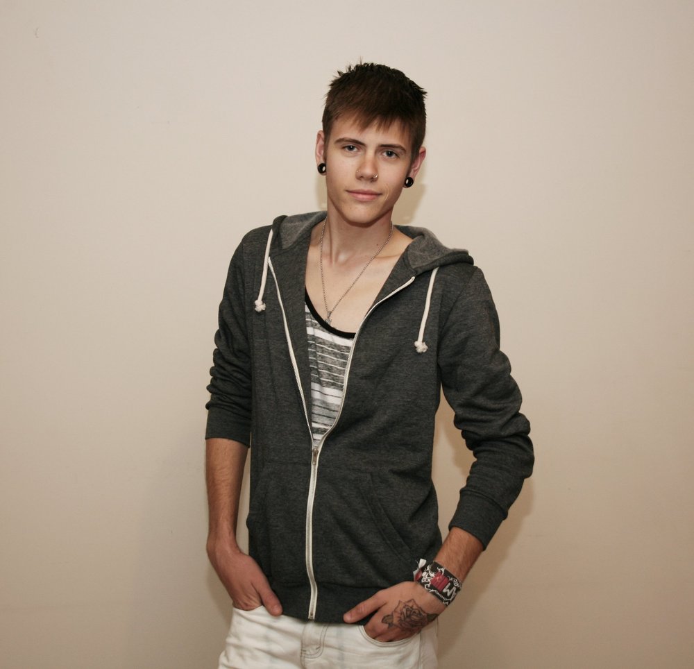 Person wearing a gray hoodie and white pants against a plain background.