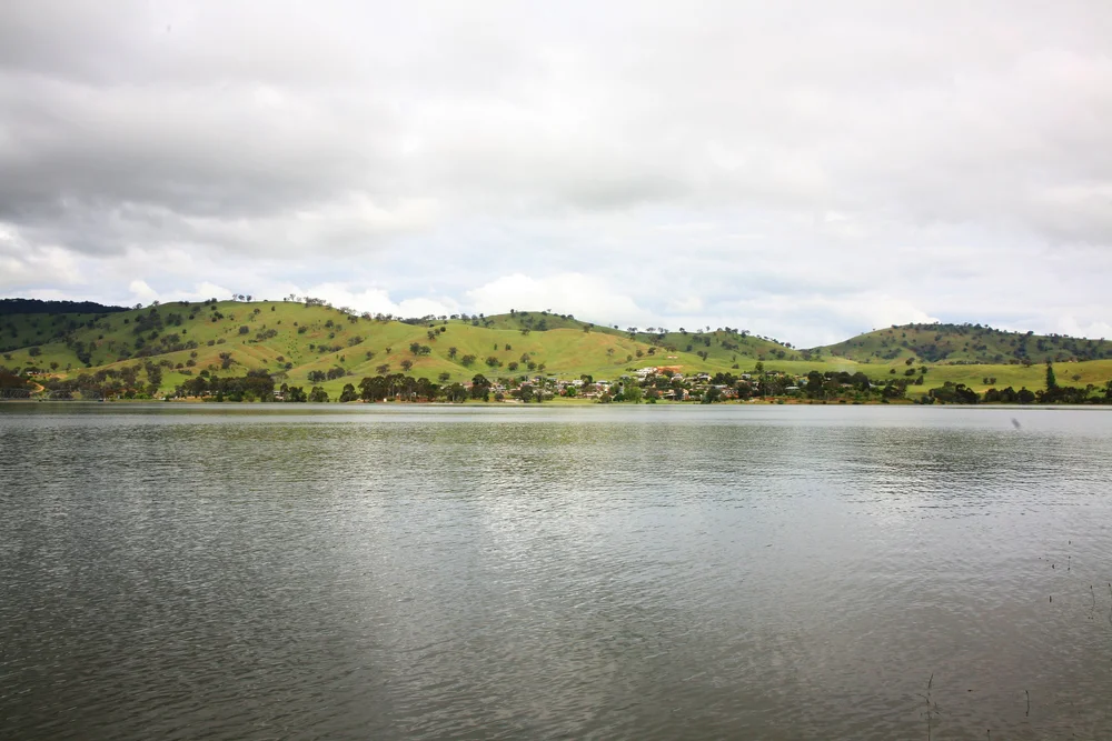 Lake surrounded by rolling green hills and partly cloudy sky