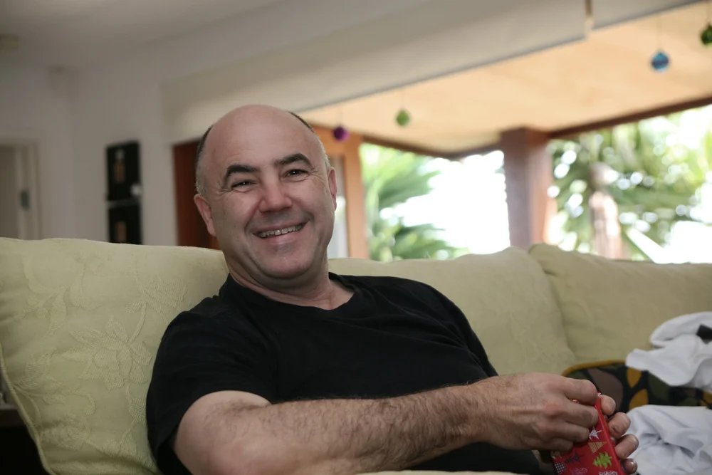 Smiling person sitting on a couch holding a gift.