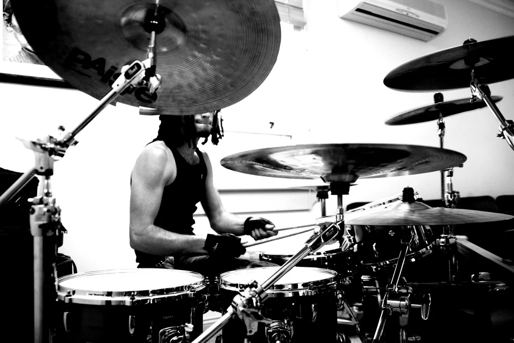 Black and white photo of a drummer playing a drum set in a music studio.