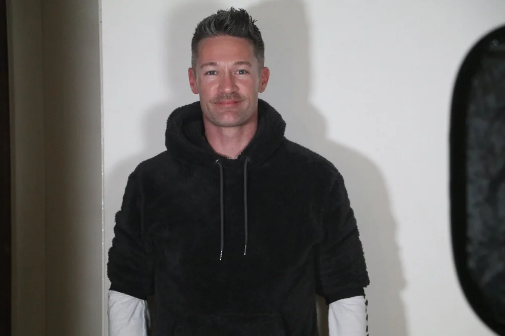 Amos in a dark jumper, photographed in 2022