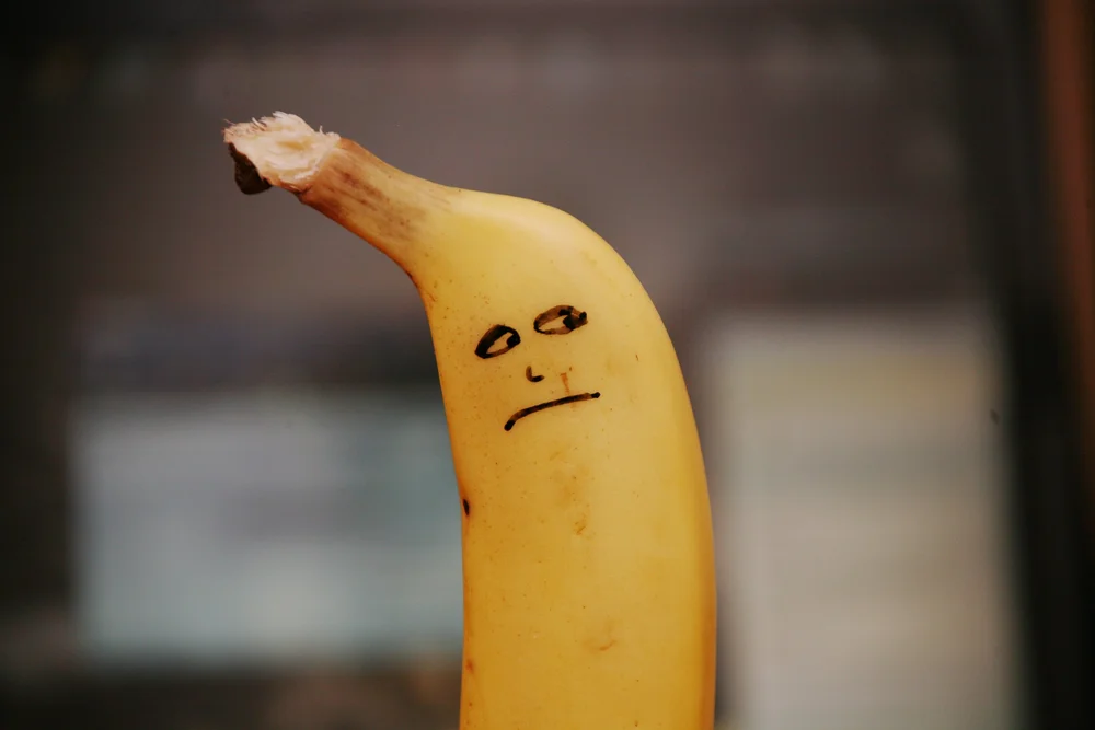 Banana with a drawn face expressing sadness or disappointment.