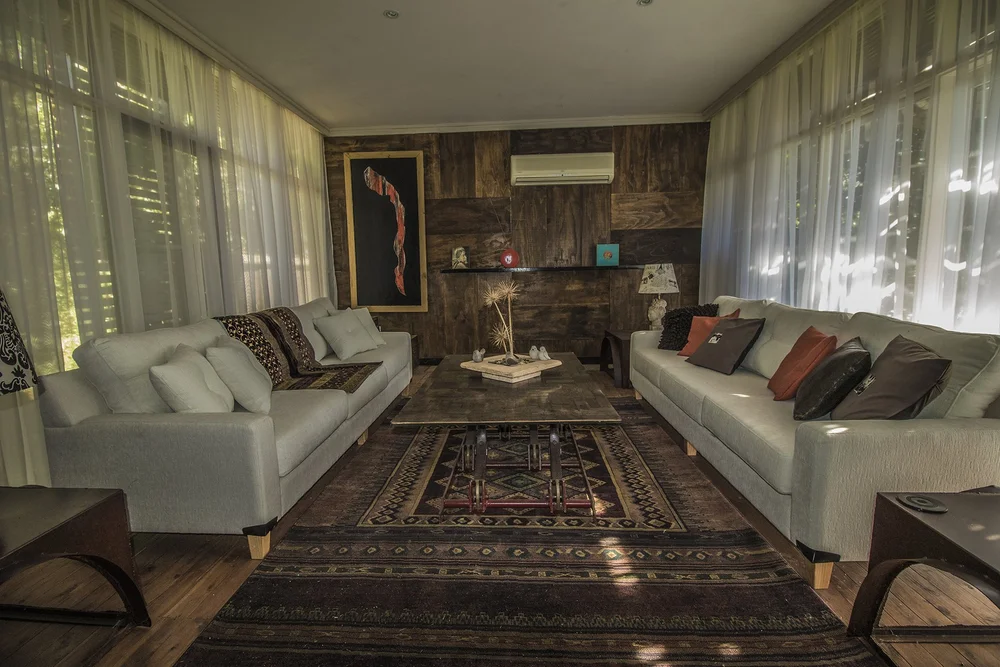A warmly lit living room with pale sofas, timber textures and patterned rugs.