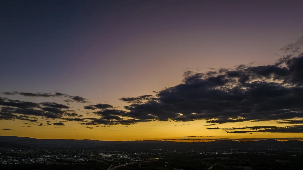 Sunset over suburban landscape with dark clouds and city lights