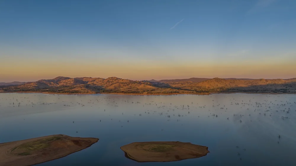 Serene lake with small islands and mountain landscape at sunset
