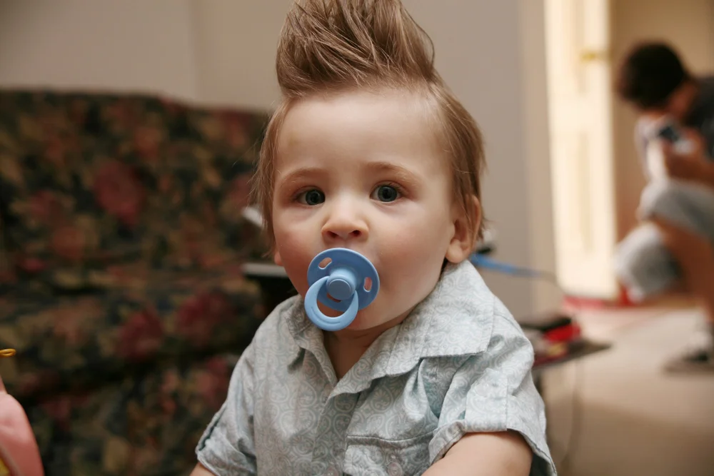 Baby with spiky hair and blue pacifier