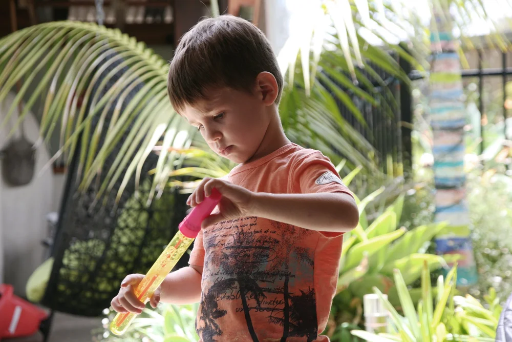 Child playing with bubble wand in garden