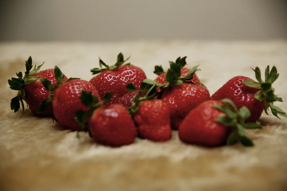 Close-up of fresh strawberries with green leaves on a soft background.