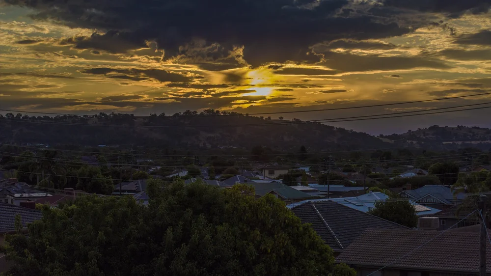 Suburban landscape with sunset and cloudy sky.