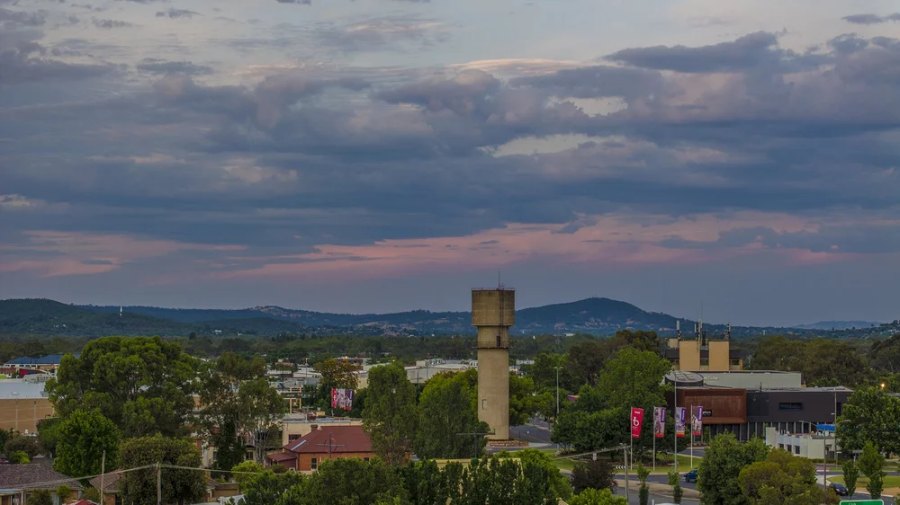 Sunset over Wagga Wagga skyline with green hills and trees