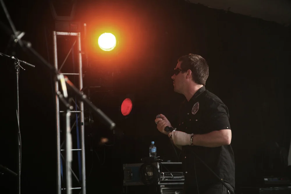 Man holding a microphone on stage with lighting equipment