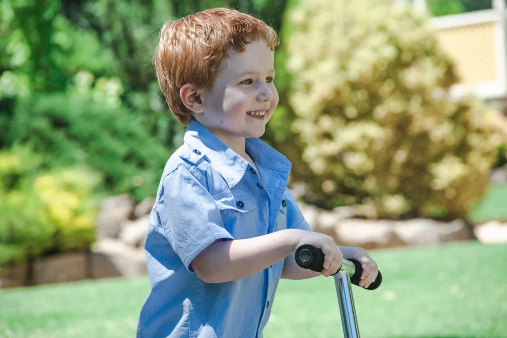 Child riding a scooter in a park