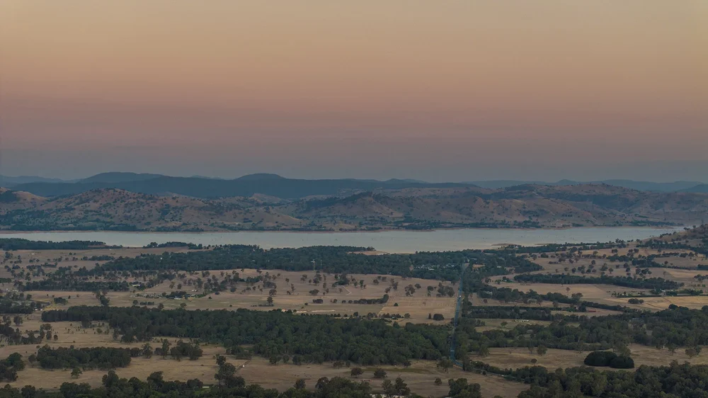 Scenic view of rural landscape with hills and a lake at sunset