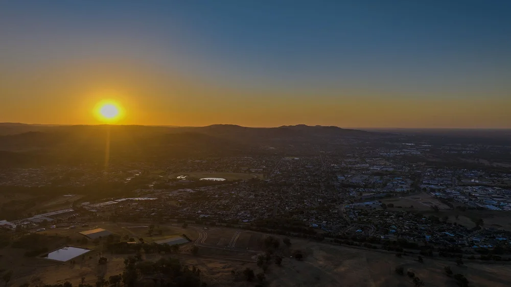 Aerial view of a town with sunset over hills.
