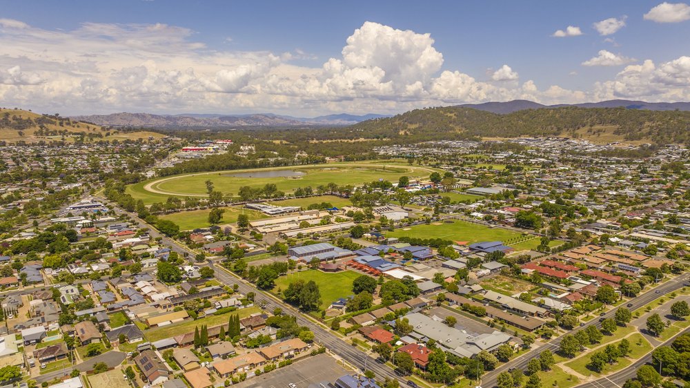 Aerial view of Wodonga, Australia, featuring residential neighborhoods, green parks, and a racecourse with a track.