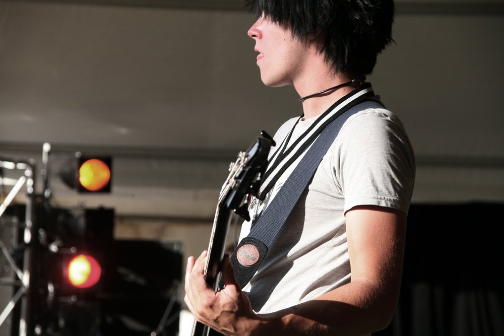 Guitarist performing on stage with lights in background