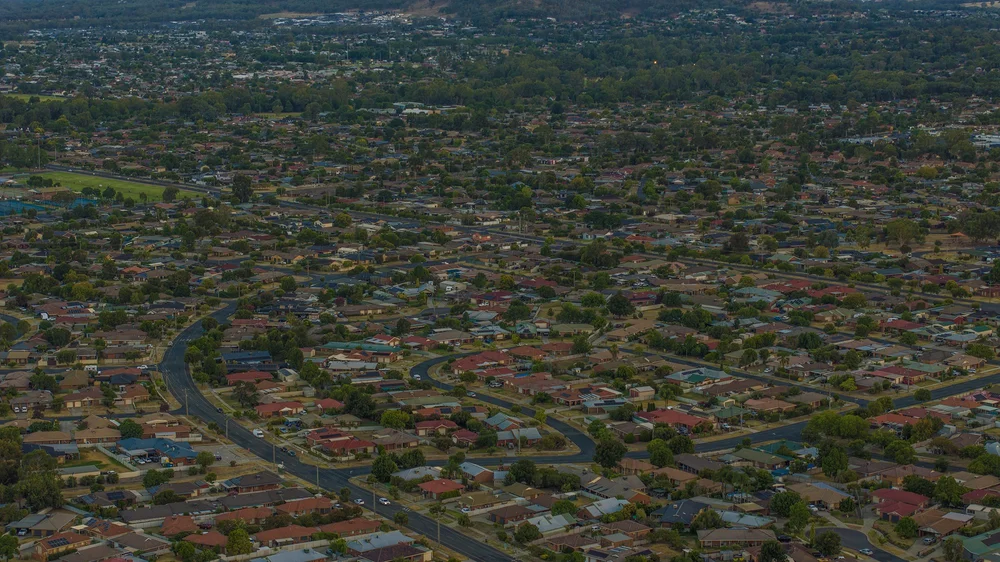 Aerial view of a suburban neighborhood with houses, trees, and roads.