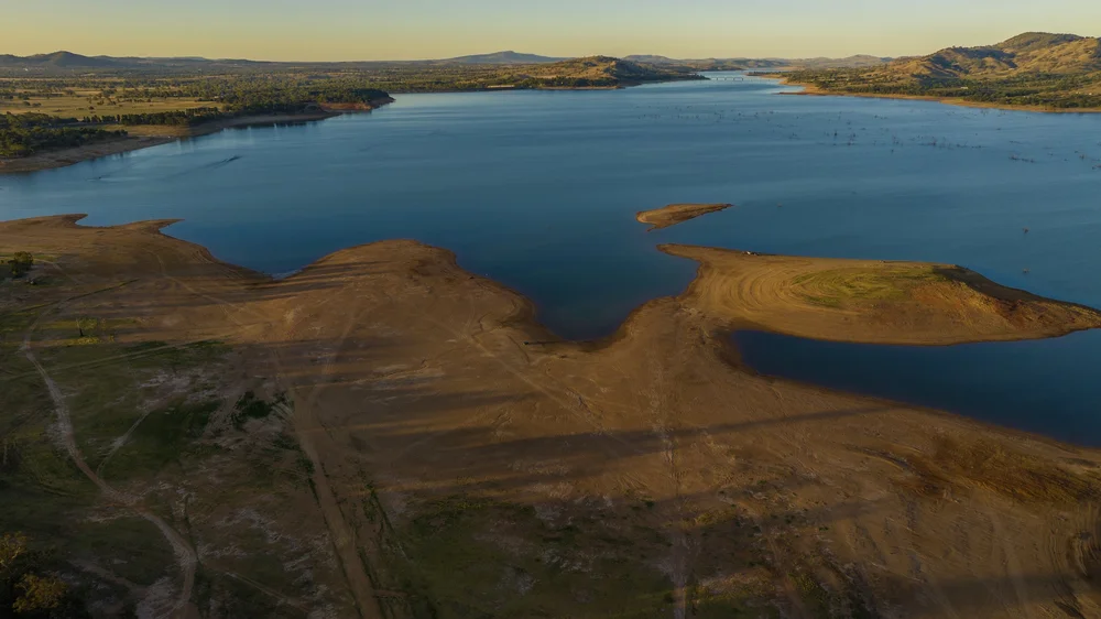 Aerial view of a large lake with sandy shorelines and small islands surrounded by water.