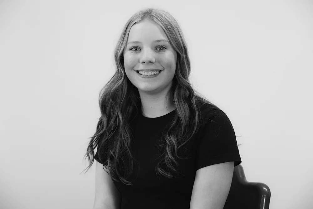 Black and white portrait of a smiling person with long hair.