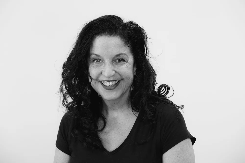Black and white portrait of a woman with curly hair smiling at the camera.