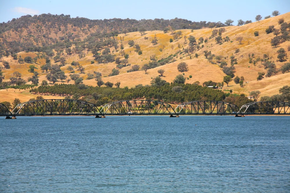 Bridge crossing over a lake with hills in the background; landscape scene